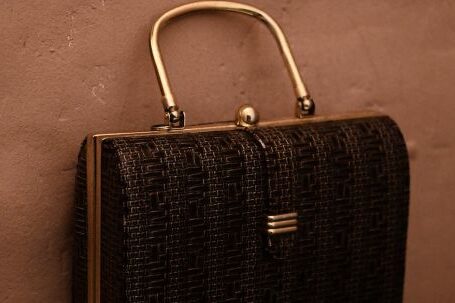 Trending Outfits - Vintage bag with golden handle placed on reflecting surface as accessory for garment