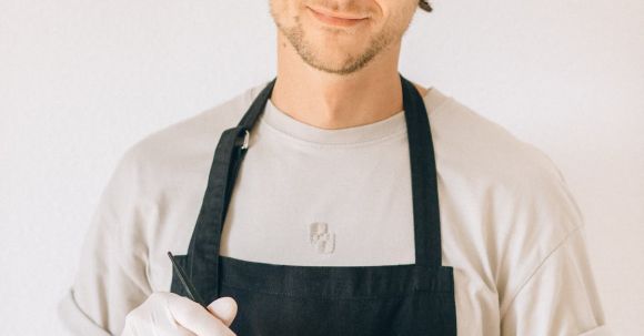 Styling - A Man in Black Apron Smiling while Holding a Plastic Bowl