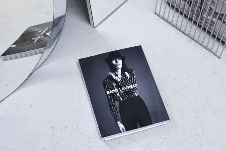 Trending Outfits - Black and white high angle fashion magazine placed on table and reflecting in geometrical mirror and rack with journals
