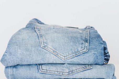 Trending Outfits - Pile of denim pants of different shades of blue placed on white shelf